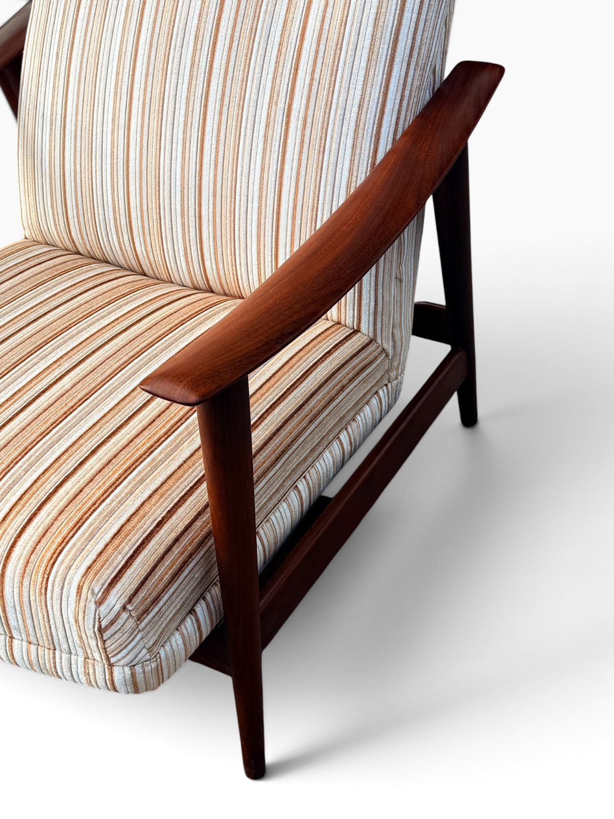 Curved walnut armrest and striped upholstery detail