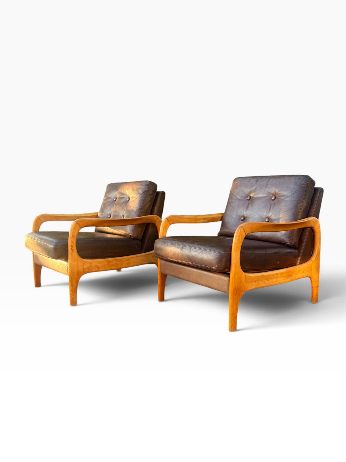 Pair of brown leather lounge chairs, angled view