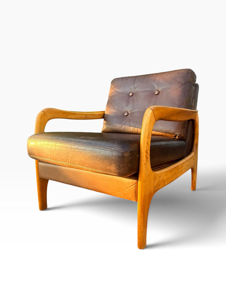 Single Danish leather armchair showing sculpted maple arm