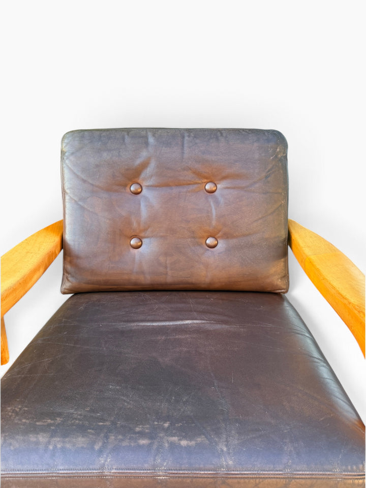 Leather seat cushion and tufted back showing vintage wear