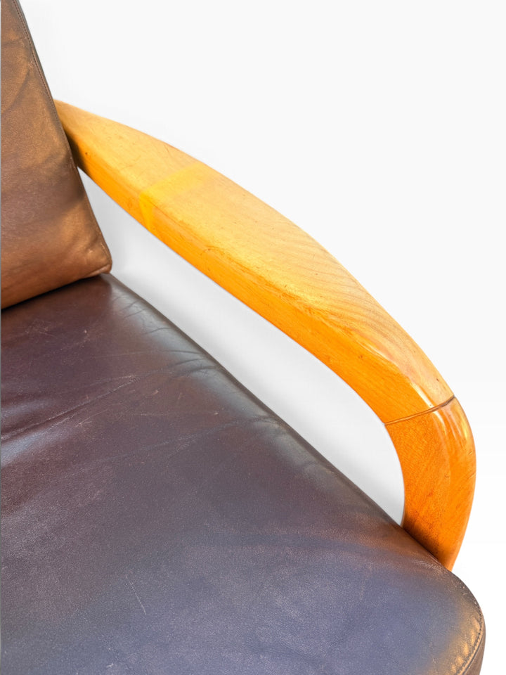 Close-up of sculpted maple arm and leather seat