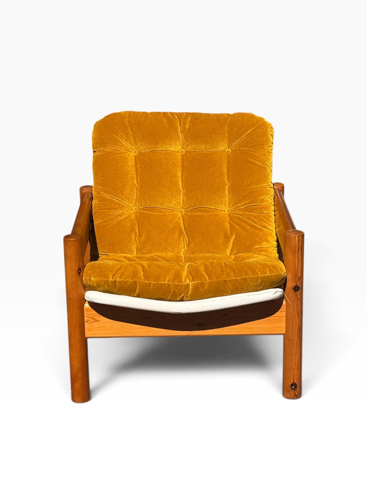 Front view of the pine lounge armchair showing the button-tufted mustard velvet seat and back