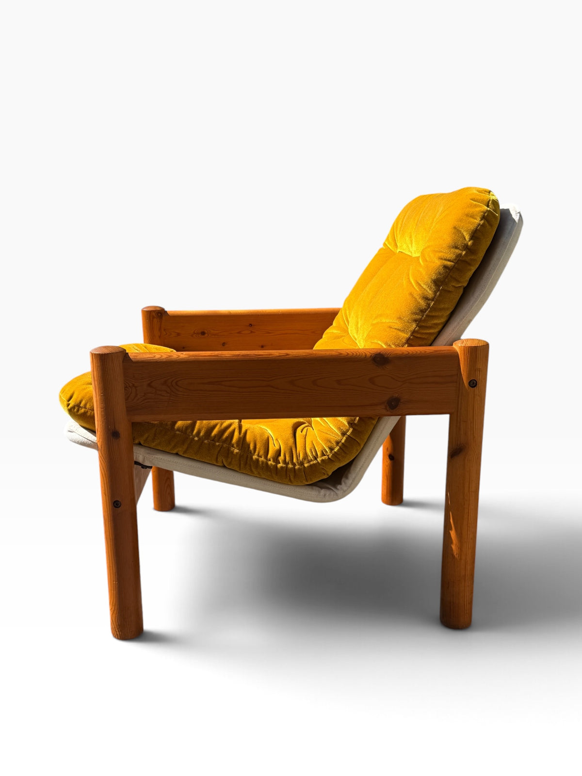 Side profile of the Danish pine armchair showing the canvas sling and reclined seat