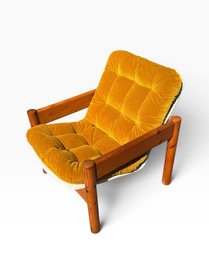 Elevated three-quarter view of the tufted mustard velvet cushion in the pine frame