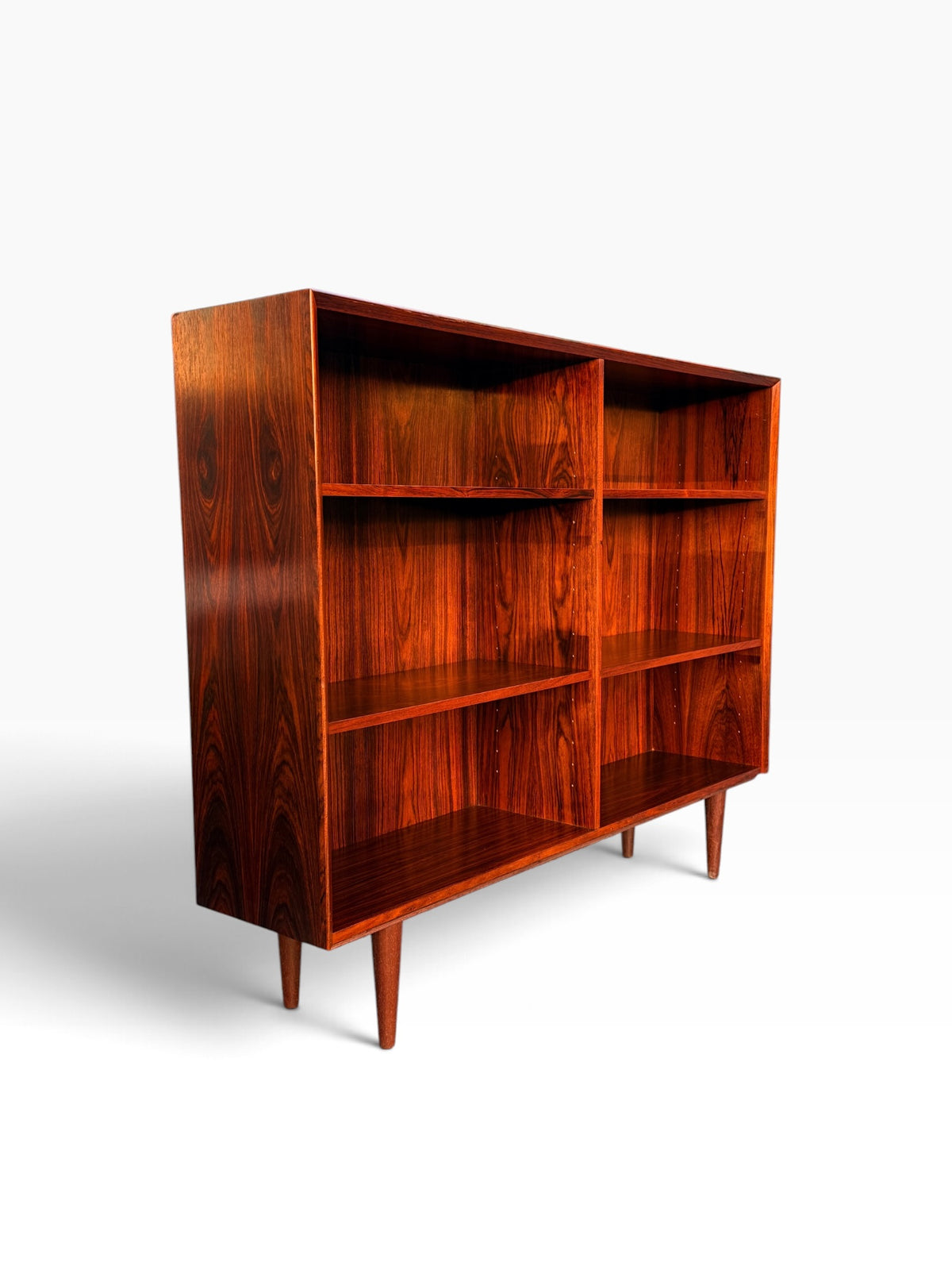 Mid-century Danish rosewood bookcase, three-quarter view showing two open bays and tapered legs