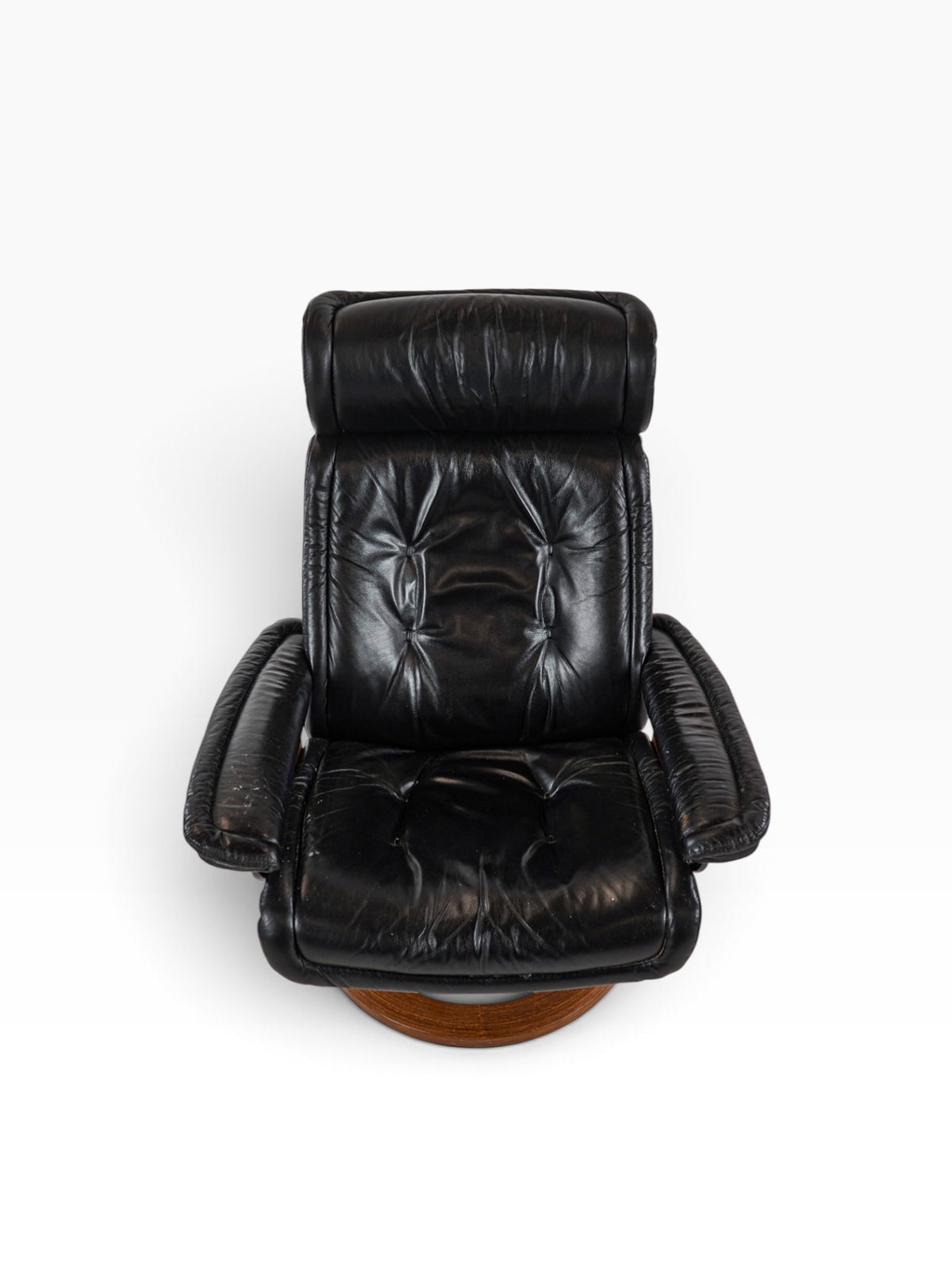 Front view of the Stressless chair showing buttoned black leather seat and adjustable headrest
