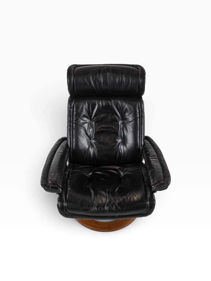 Front view of the Stressless chair showing buttoned black leather seat and adjustable headrest