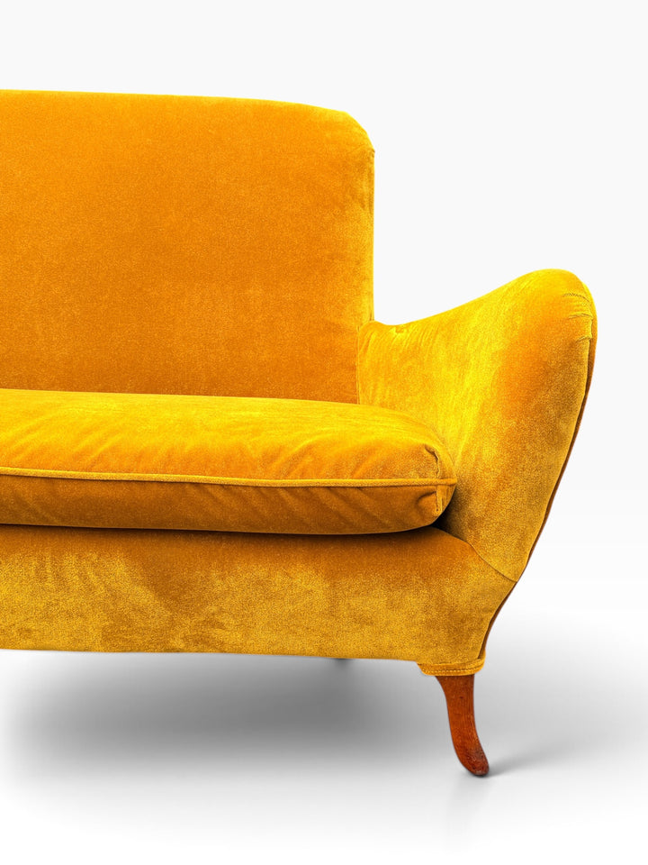 Detail of the flared upswept wing arm and piped velvet upholstery