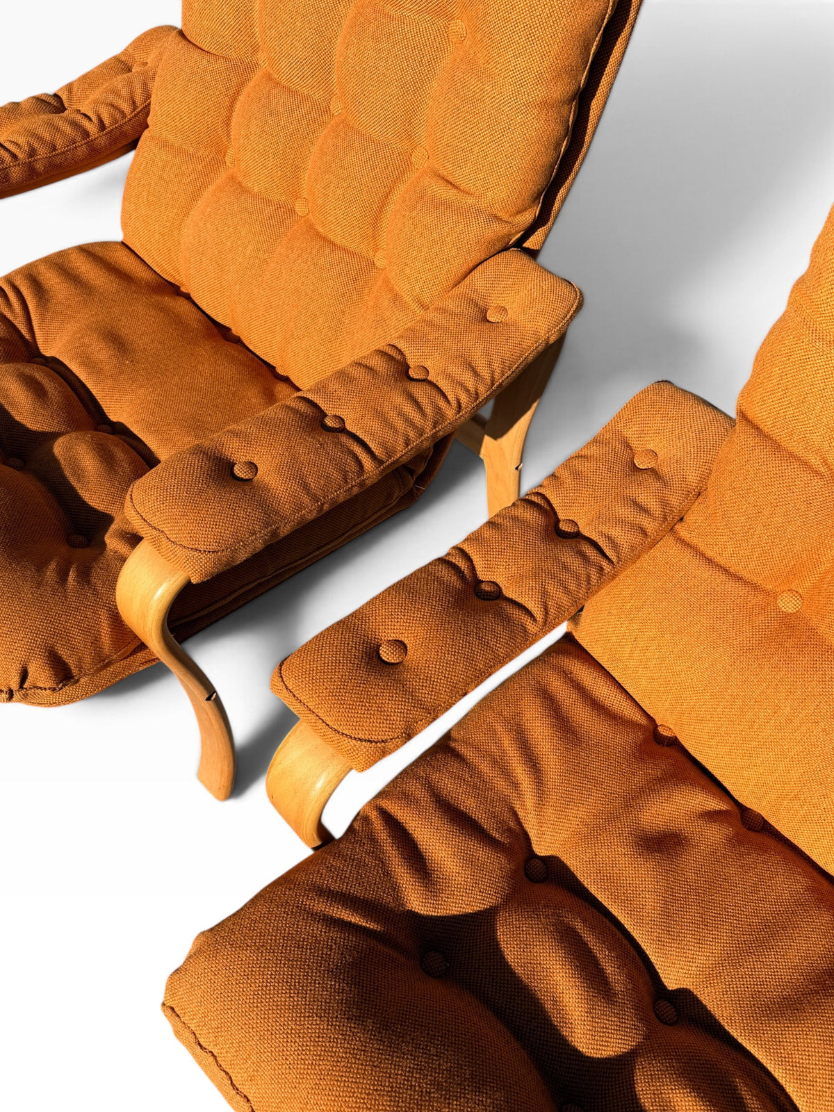 Close-up of button-tufted arm pads and burnt orange cushions