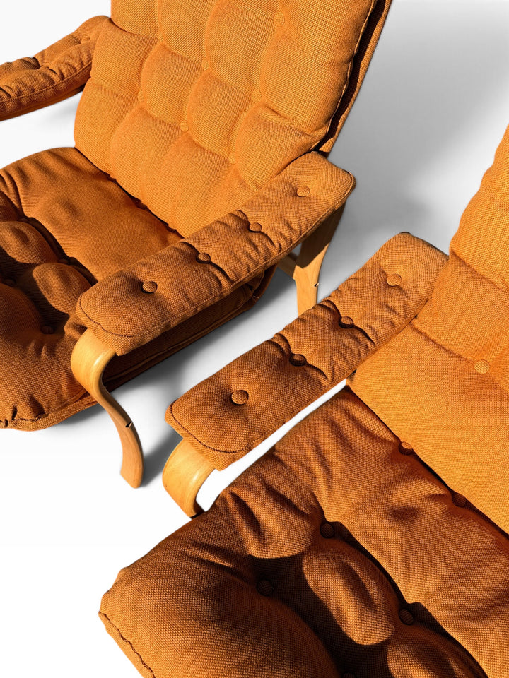 Close-up of button-tufted arm pads and burnt orange cushions