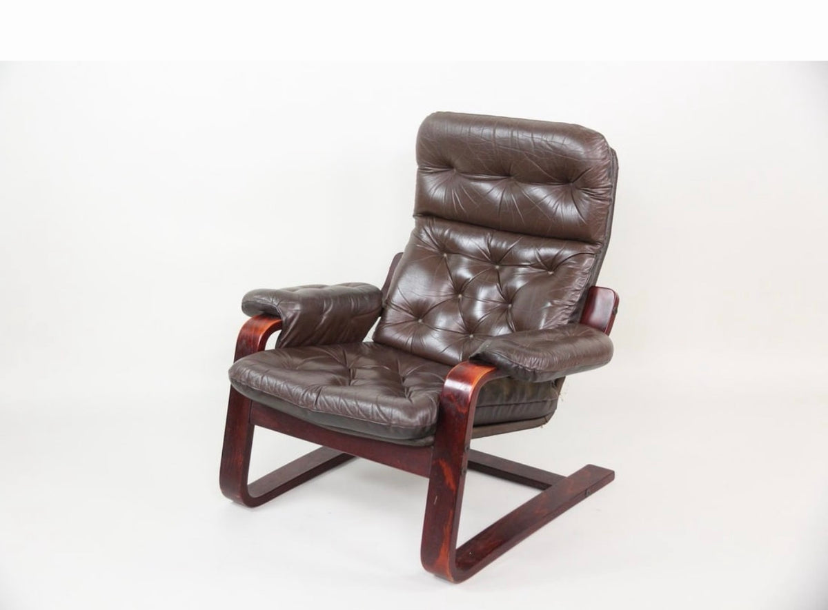 Three-quarter view of the cantilever leather lounge chair on its rosewood-toned bentwood sled base
