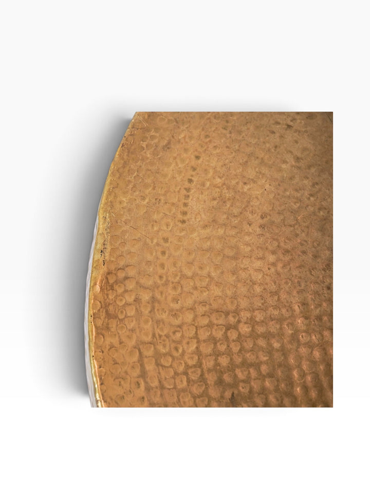 Close-up of the hand-hammered brass surface and rim showing patina and light surface wear