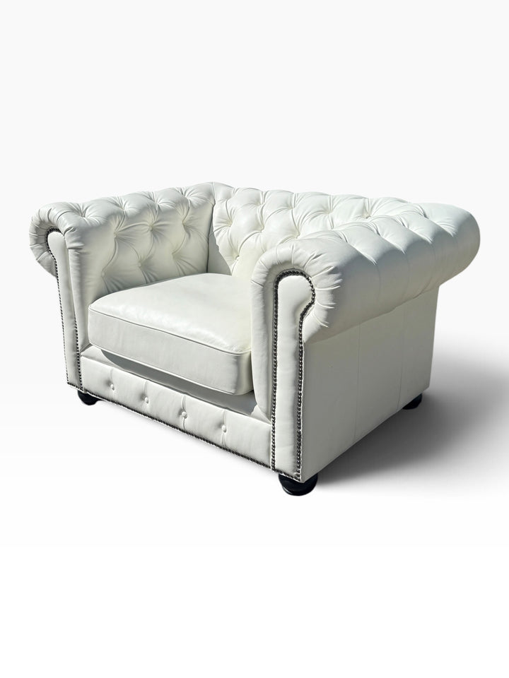 Three-quarter view of white leather Chesterfield chair showing rolled arms