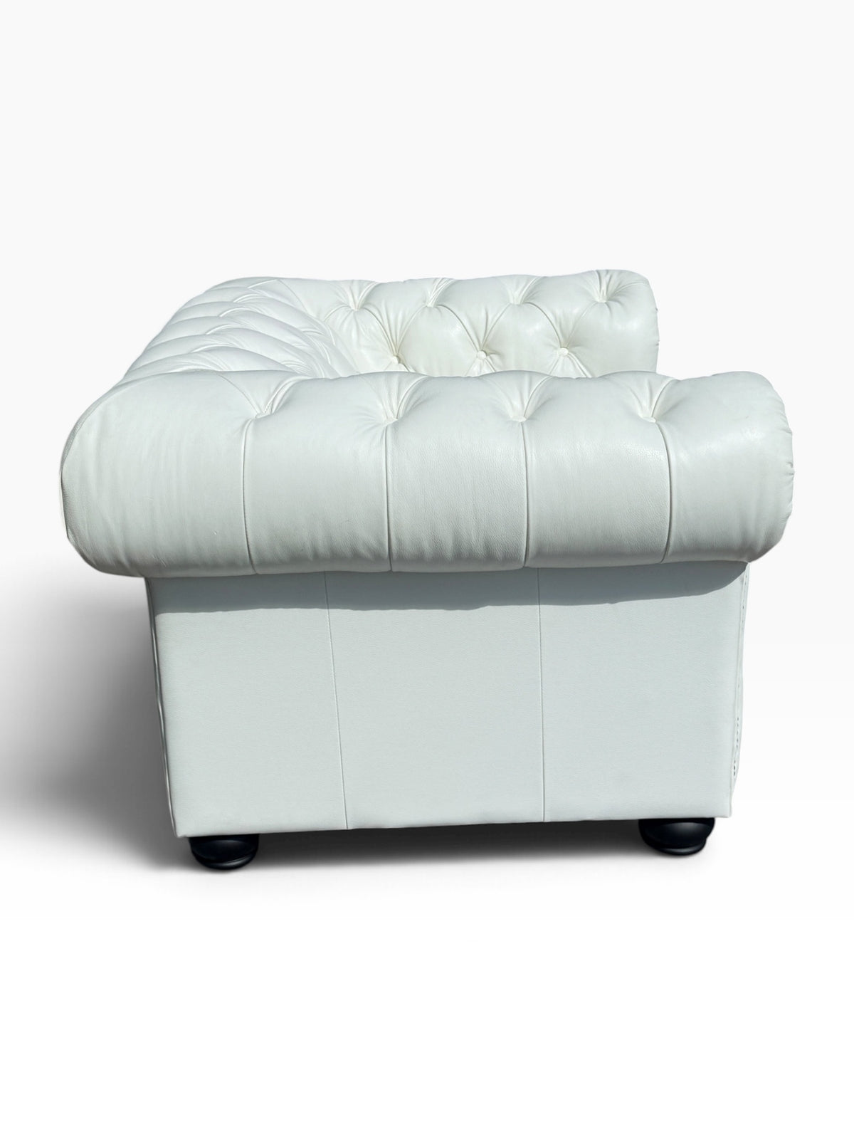 Back view of white leather Chesterfield chair showing tufted back and side panel